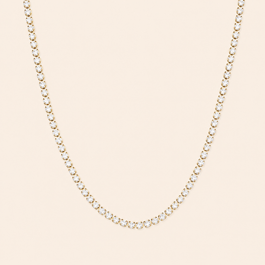 Delicate gold necklace with small diamonds on a beige background