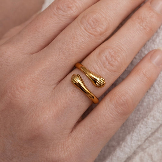 Gold ring on a person's finger with a neutral background
