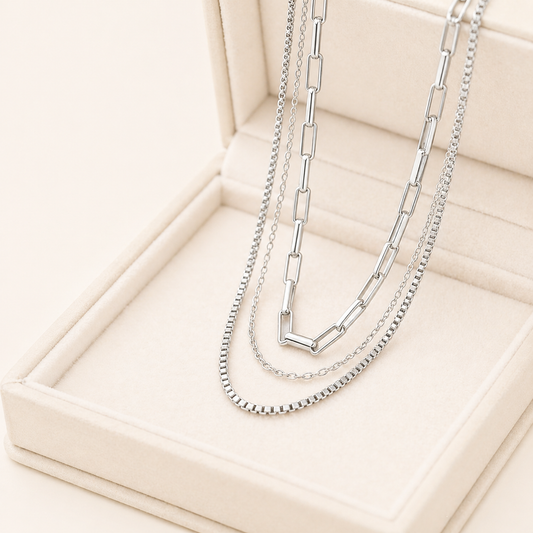 3 layered silver necklaces on a beige jewelry box