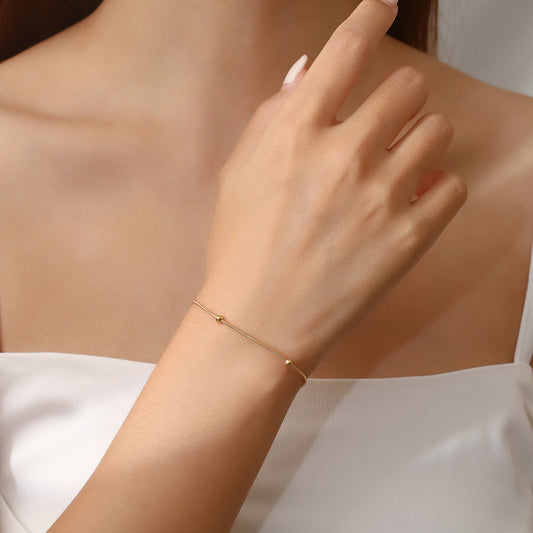 Gold bracelet on a hand against a beige fabric background