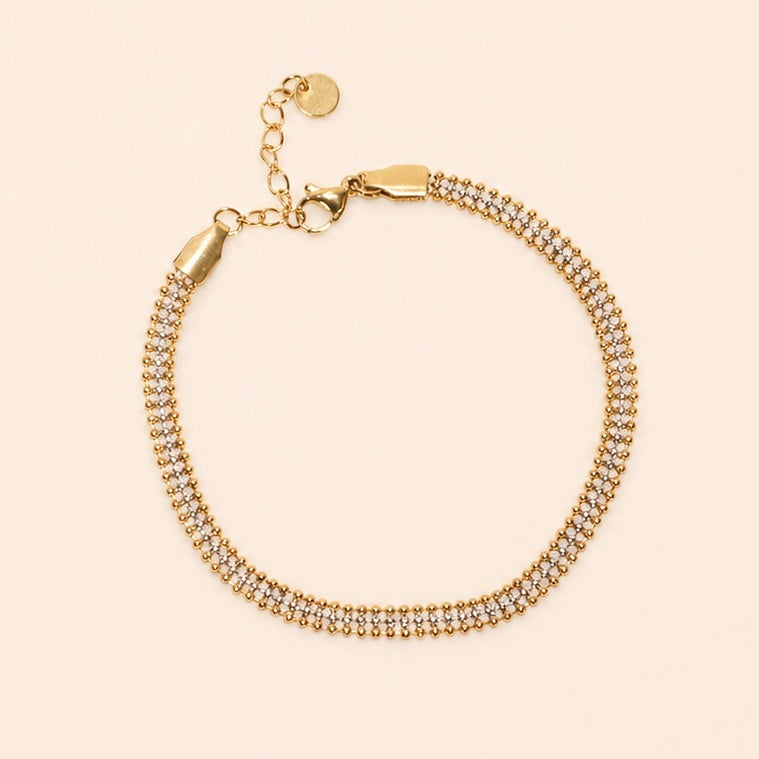 Gold and silver beaded bracelet on a beige background