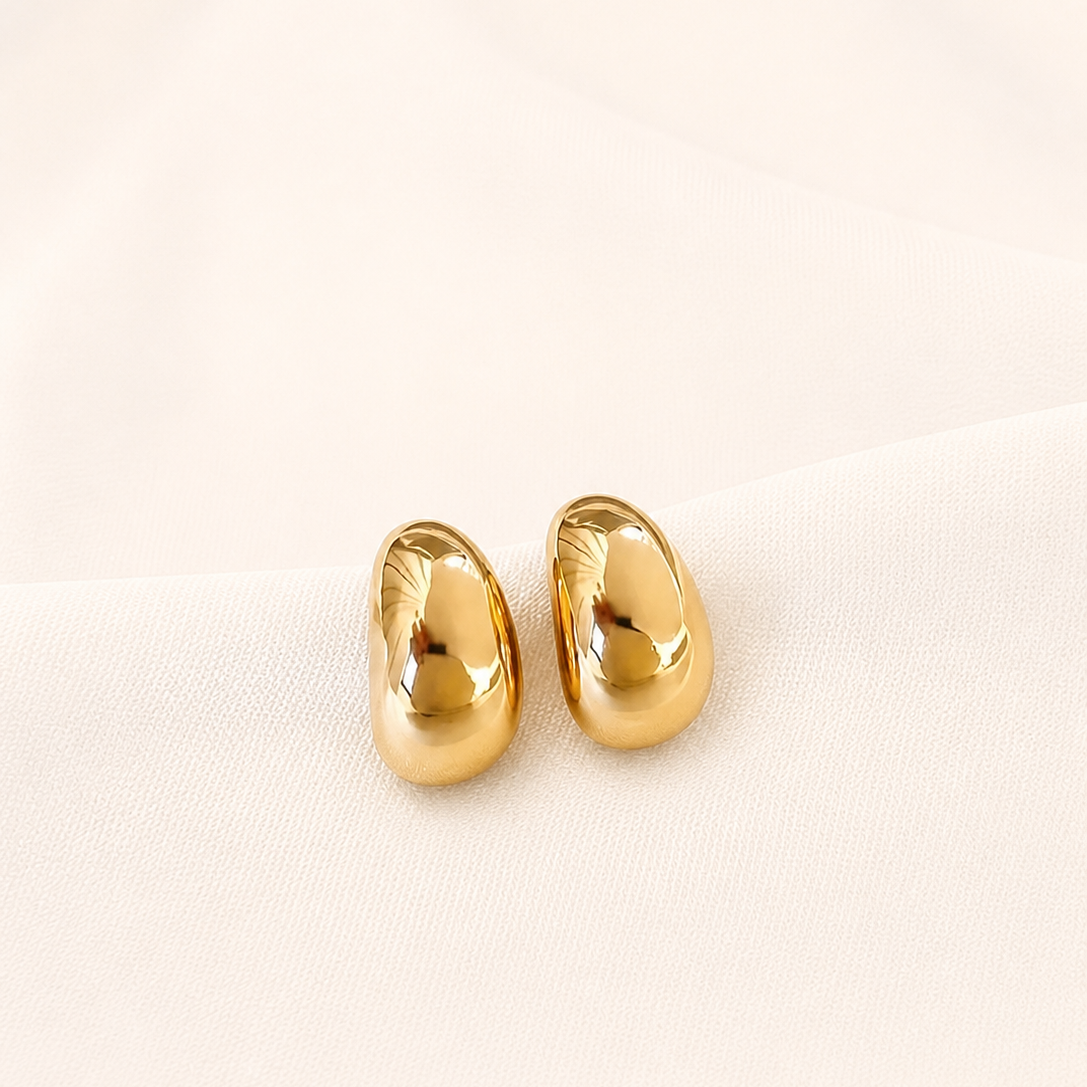 Pair of gold earrings on a light beige background