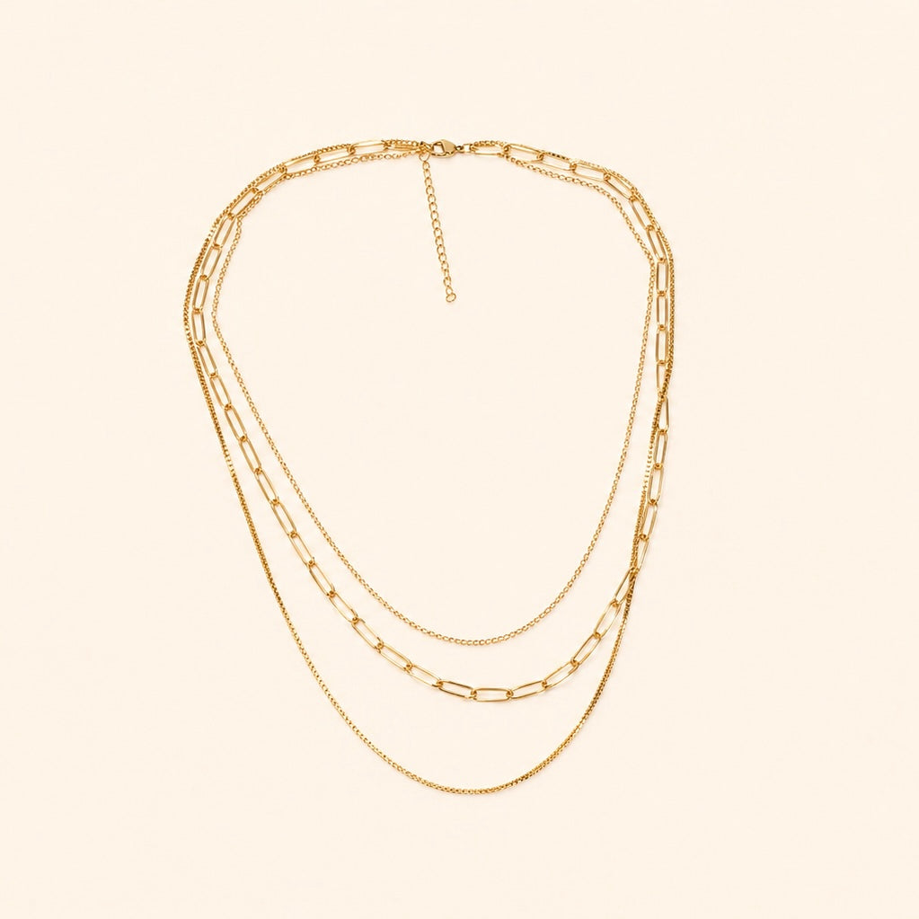 Layered Gold chain necklace on a beige background
