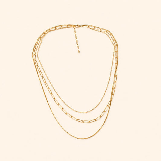 Layered Gold chain necklace on a beige background