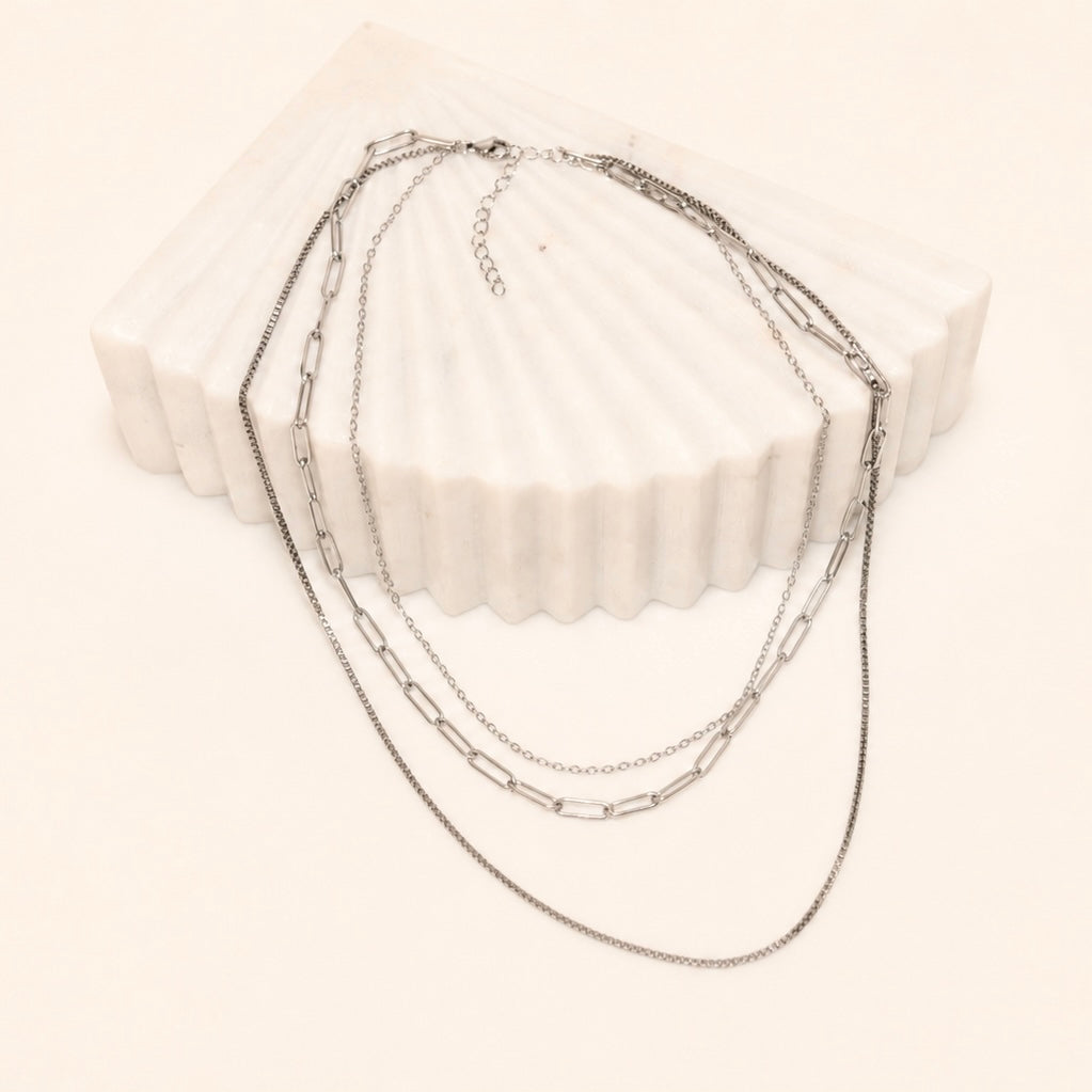 Layered Silver chain necklace on a white block with a white background