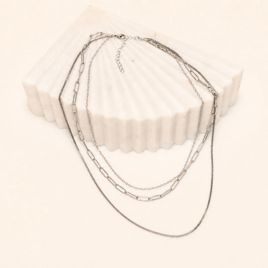 Layered Silver chain necklace on a white block with a white background
