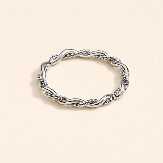 Silver ring with braided design on a beige background